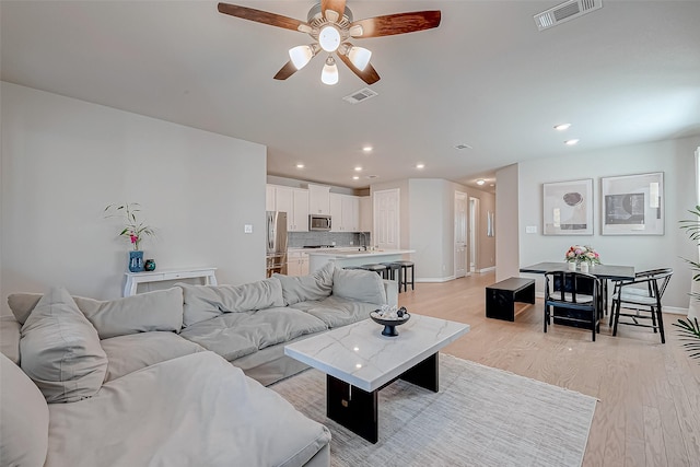 living room with recessed lighting, visible vents, and light wood finished floors