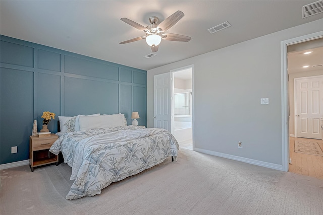 bedroom with visible vents, light colored carpet, and a decorative wall