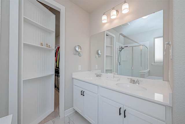 full bathroom with a spacious closet, visible vents, a stall shower, and a sink