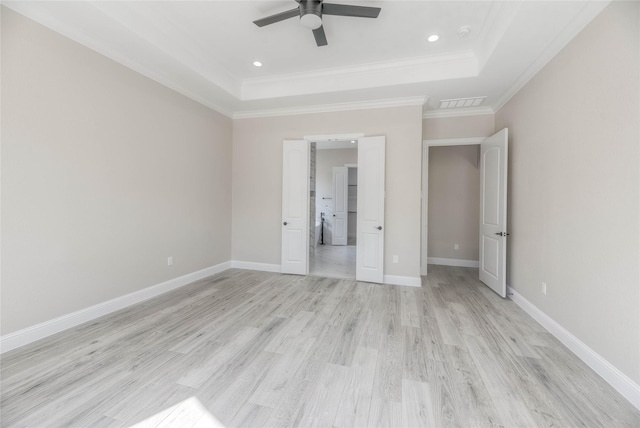 unfurnished bedroom featuring light wood-style flooring, baseboards, crown molding, and a tray ceiling