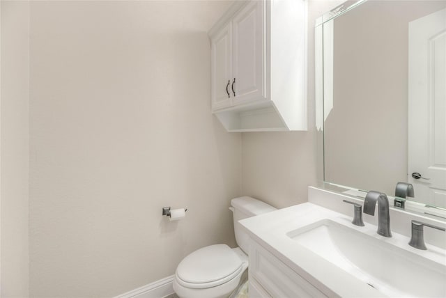 bathroom featuring toilet, vanity, and baseboards