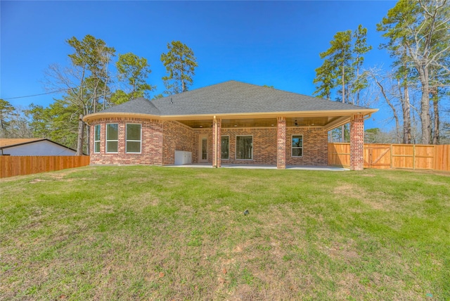 back of property featuring a yard, a patio, brick siding, and a fenced backyard