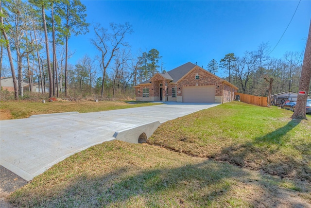 view of front of house featuring fence, a front yard, driveway, stone siding, and an attached garage