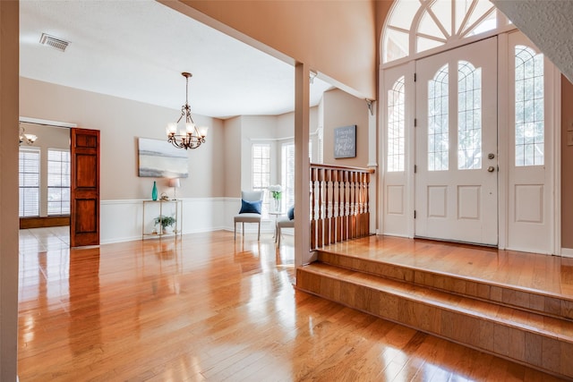 entrance foyer featuring visible vents, light wood-style floors, and an inviting chandelier