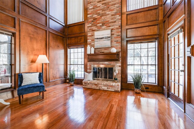 unfurnished living room with a brick fireplace, light wood-type flooring, and a high ceiling