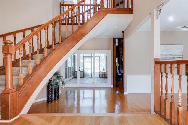 stairway with a high ceiling, wood finished floors, and baseboards