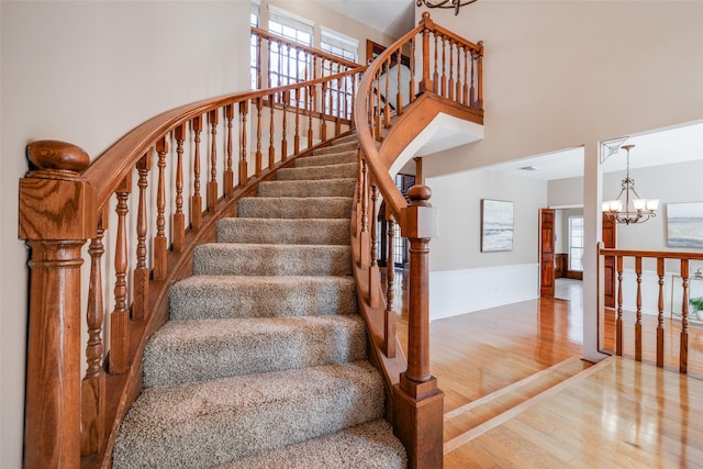 stairway with a chandelier, a high ceiling, and wood finished floors