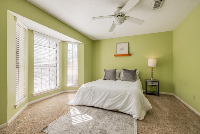 carpeted bedroom with visible vents, baseboards, and ceiling fan