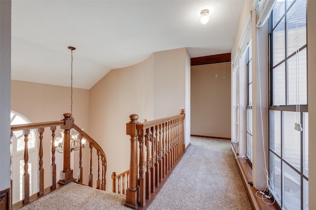 hall with vaulted ceiling, carpet flooring, an upstairs landing, and a wealth of natural light