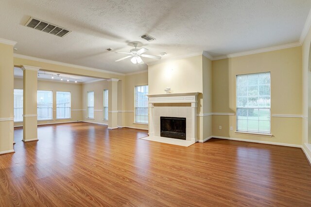 1373 El Camino Village Dr, Houston, TX 77058 - unfurnished living room featuring visible vents, a healthy amount of sunlight, decorative columns, a tile fireplace, and wood finished floors