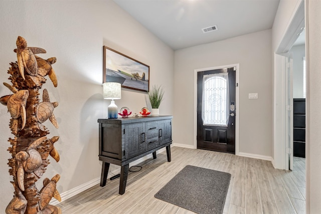 foyer entrance featuring visible vents, baseboards, and light wood-style floors