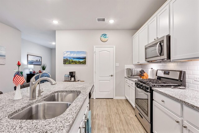 kitchen featuring tasteful backsplash, visible vents, stainless steel appliances, and a sink