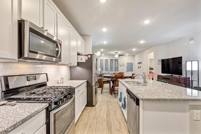 kitchen featuring a sink, stainless steel appliances, open floor plan, and white cabinetry