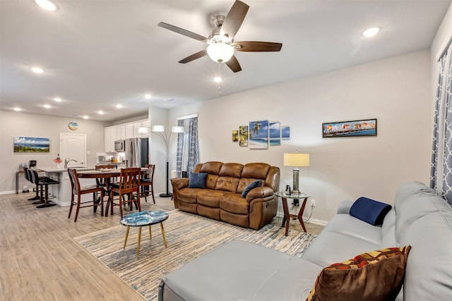 living room featuring recessed lighting, light wood-style floors, and baseboards