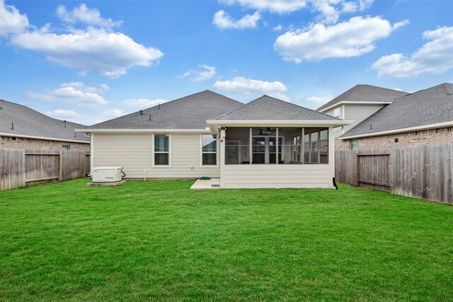 back of property with a lawn, a shingled roof, a fenced backyard, and a sunroom