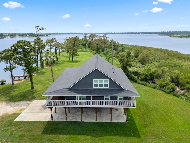 back of property with a yard, a patio area, and a water view