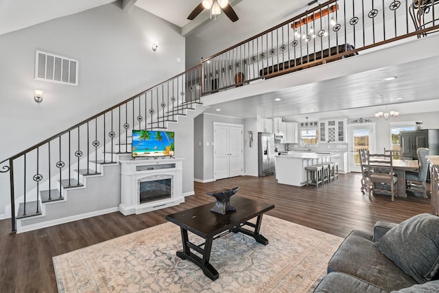 living area with stairs, a glass covered fireplace, visible vents, and dark wood-style flooring