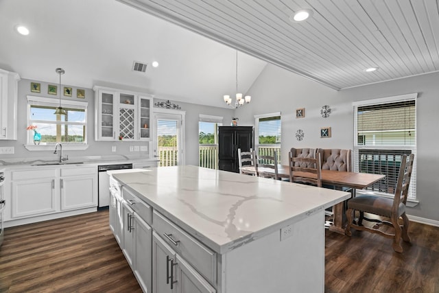 kitchen with visible vents, light stone counters, a kitchen island, dark wood finished floors, and lofted ceiling