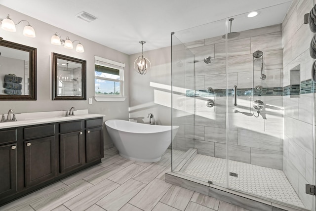 full bath with visible vents, a shower stall, double vanity, a freestanding tub, and a sink