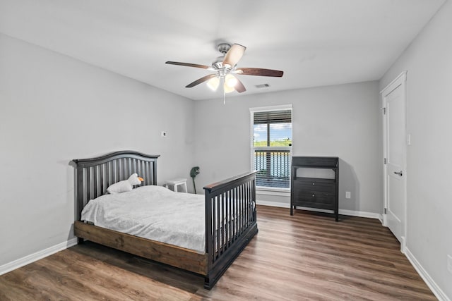 bedroom featuring visible vents, a ceiling fan, baseboards, and wood finished floors