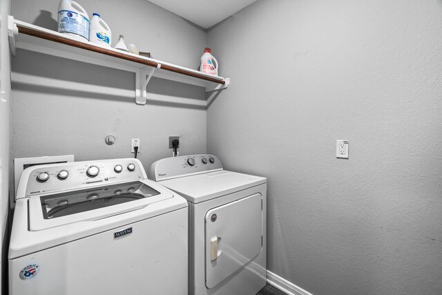 washroom with a textured wall, laundry area, and washer and clothes dryer