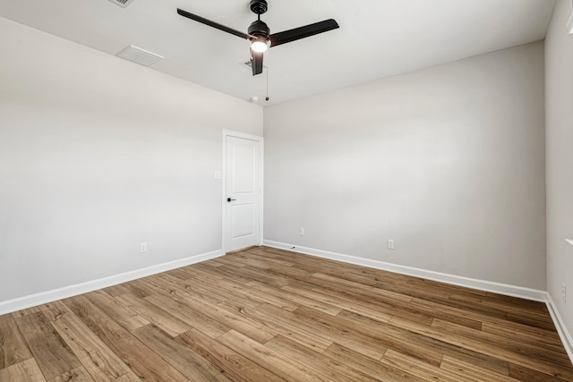 spare room with visible vents, wood finished floors, baseboards, and ceiling fan