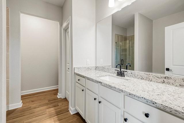 full bath with a stall shower, baseboards, wood finished floors, and vanity