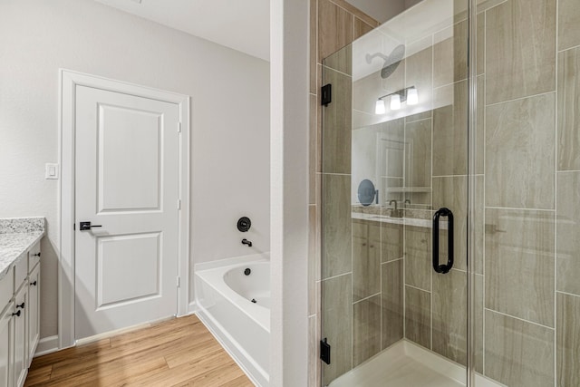 full bath featuring wood finished floors, a stall shower, vanity, and a bath