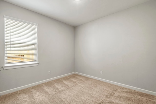 unfurnished room with light carpet and baseboards