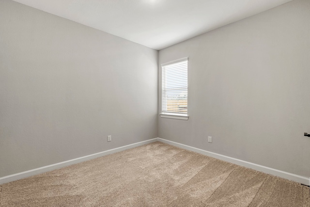 empty room featuring carpet and baseboards