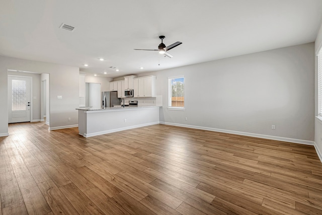 unfurnished living room with a ceiling fan, visible vents, baseboards, light wood finished floors, and recessed lighting