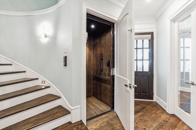 foyer with elevator, crown molding, stairs, and wood finished floors