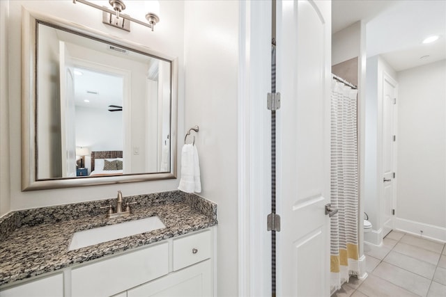 ensuite bathroom with baseboards, toilet, ensuite bathroom, tile patterned floors, and vanity