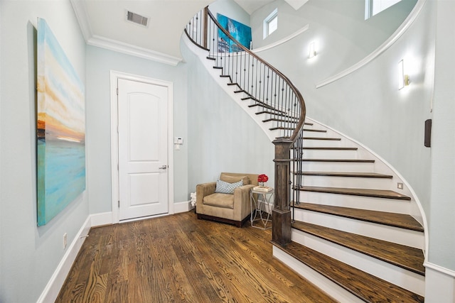 foyer entrance featuring stairway, wood finished floors, visible vents, baseboards, and crown molding