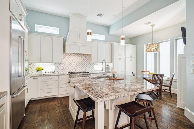 kitchen with custom exhaust hood, visible vents, dark wood-type flooring, and built in fridge