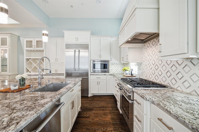 kitchen featuring premium range hood, a sink, dark wood-type flooring, built in appliances, and backsplash