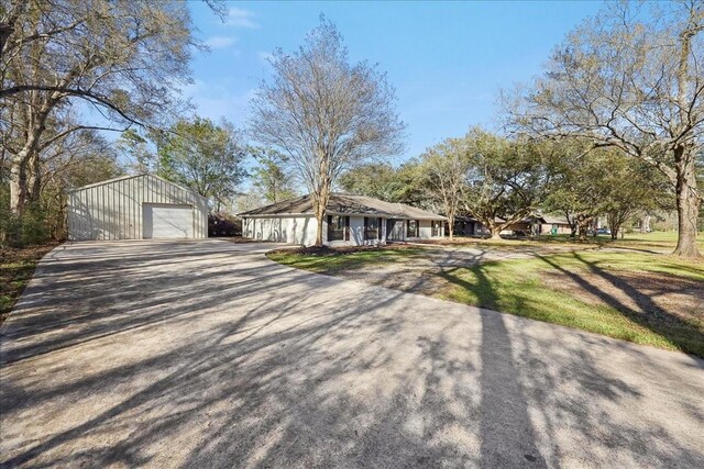 view of front of property featuring a front lawn, an outbuilding, a detached garage, and driveway