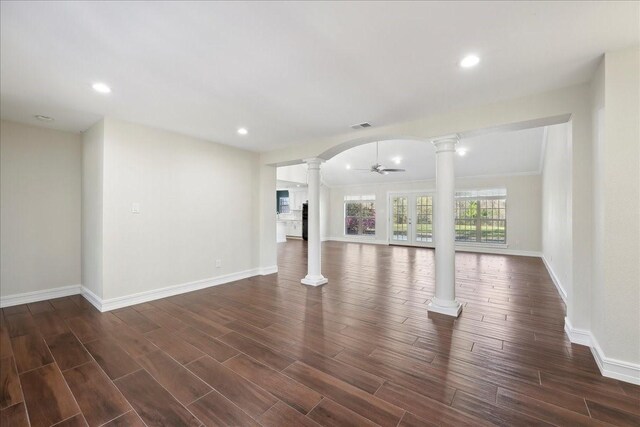 unfurnished living room with visible vents, dark wood-type flooring, baseboards, ornate columns, and a ceiling fan