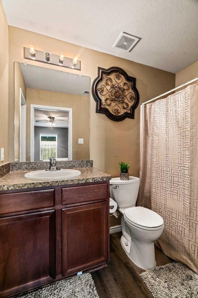 bathroom with visible vents, toilet, vanity, wood finished floors, and a textured ceiling