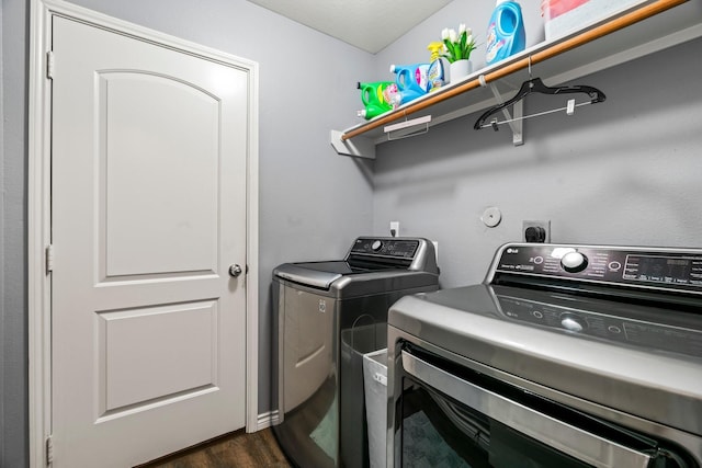 laundry room with dark wood-type flooring, washing machine and dryer, and laundry area