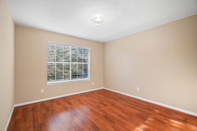 unfurnished room with wood finished floors, baseboards, and a textured ceiling