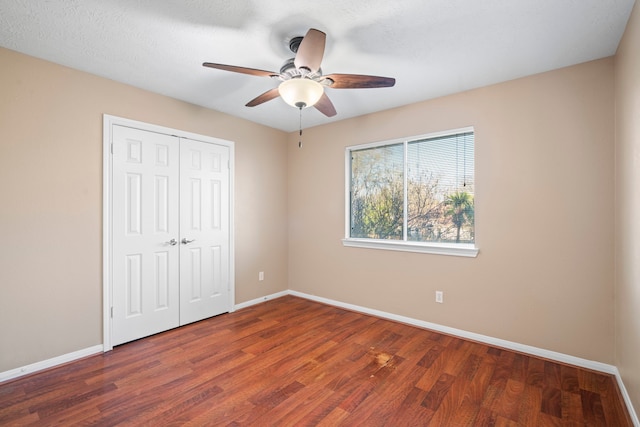 unfurnished bedroom featuring ceiling fan, a closet, baseboards, and wood finished floors