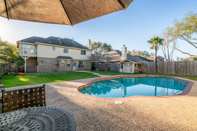 view of pool with an outbuilding, a shed, a lawn, and a fenced backyard