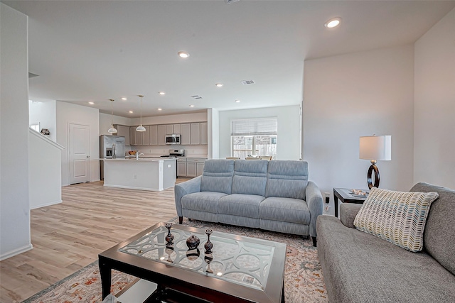 living room featuring recessed lighting, visible vents, light wood-type flooring, and baseboards