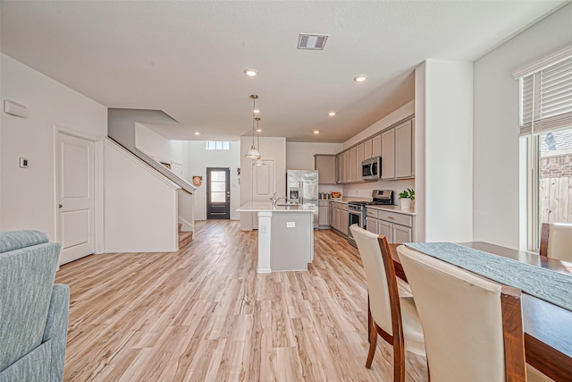 kitchen featuring visible vents, gray cabinetry, open floor plan, light countertops, and appliances with stainless steel finishes