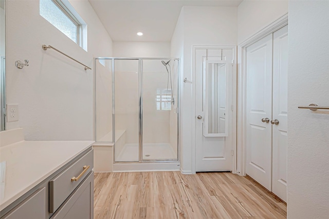 full bath with vanity, wood finished floors, and a stall shower