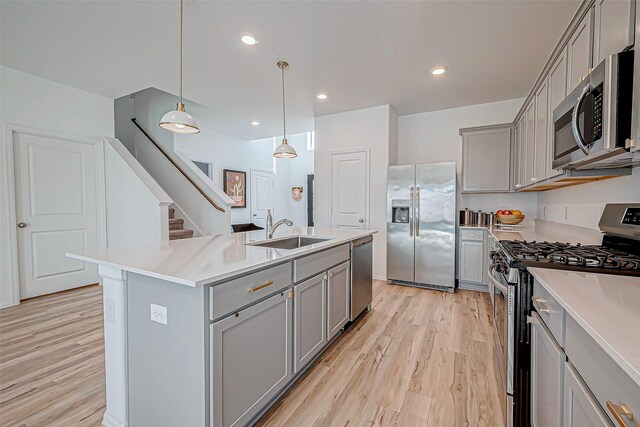 kitchen with gray cabinets, appliances with stainless steel finishes, light wood-style floors, and a sink