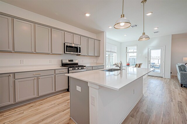 kitchen with visible vents, light wood finished floors, a sink, gray cabinetry, and appliances with stainless steel finishes