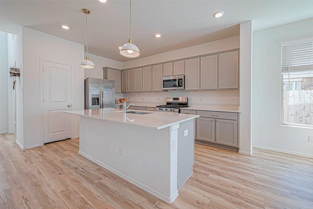 kitchen featuring gray cabinets, appliances with stainless steel finishes, light wood-style floors, and a sink