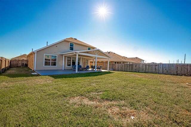 rear view of house with a patio area, a lawn, and a fenced backyard